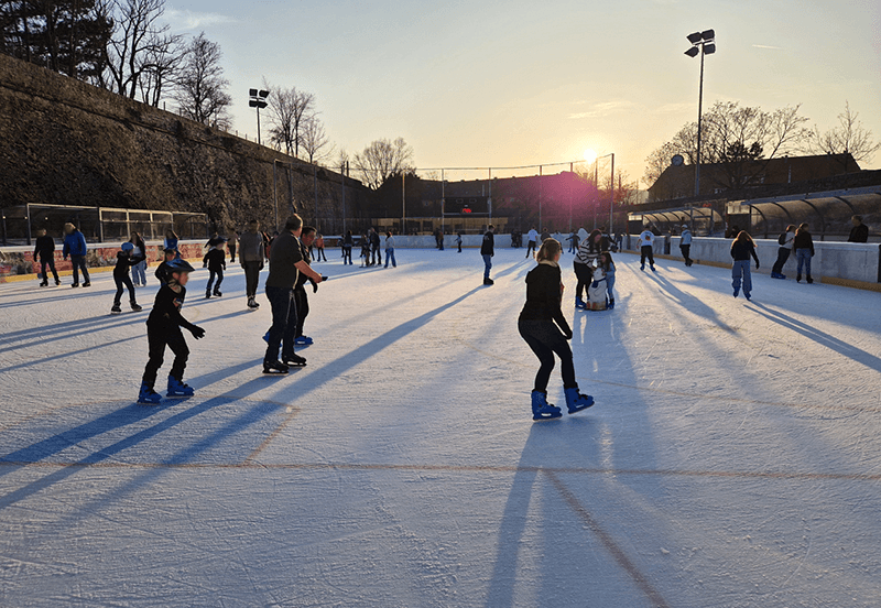  Schlittschuhläufer auf einer Eisbahn in Würzburg bei Sonnenuntergang, perfekt für Eiskunstlauf und Freizeitspaß.